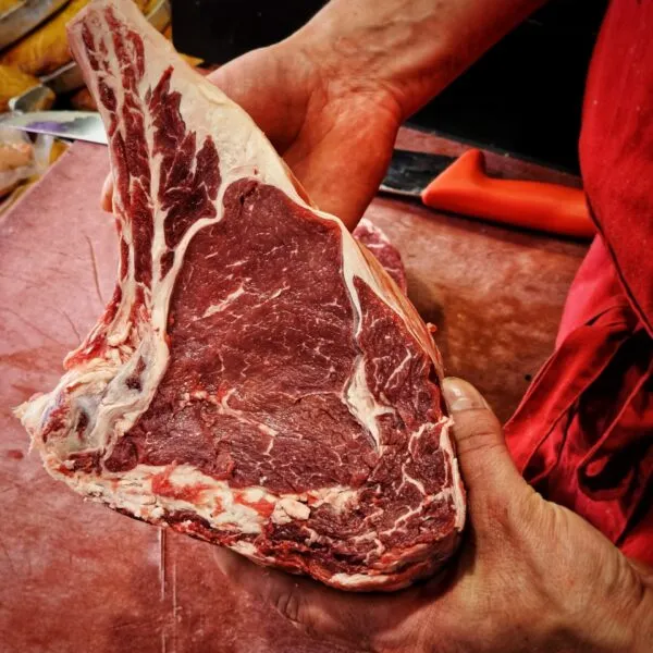 présentation d'une cote de bœuf dans les mains du boucher