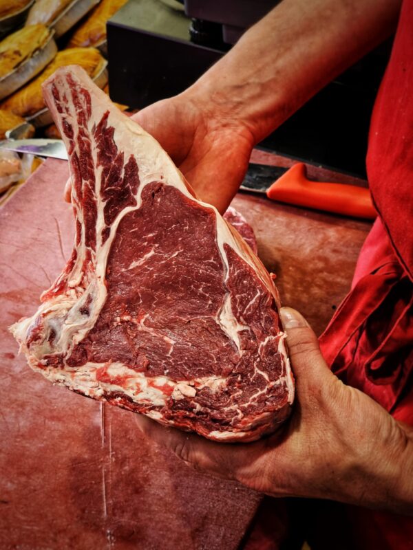 présentation d'une cote de bœuf dans les mains du boucher