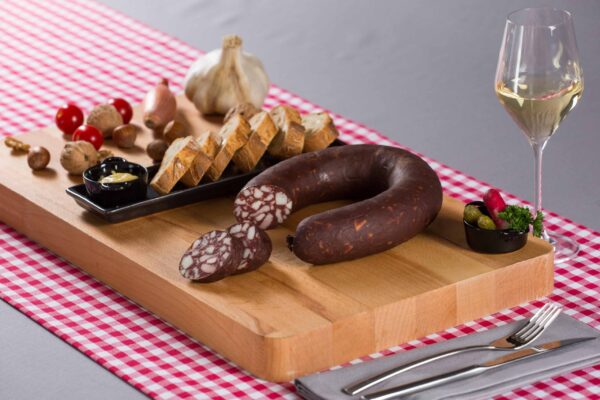 rond de saucisse noire sur planche avec pickles