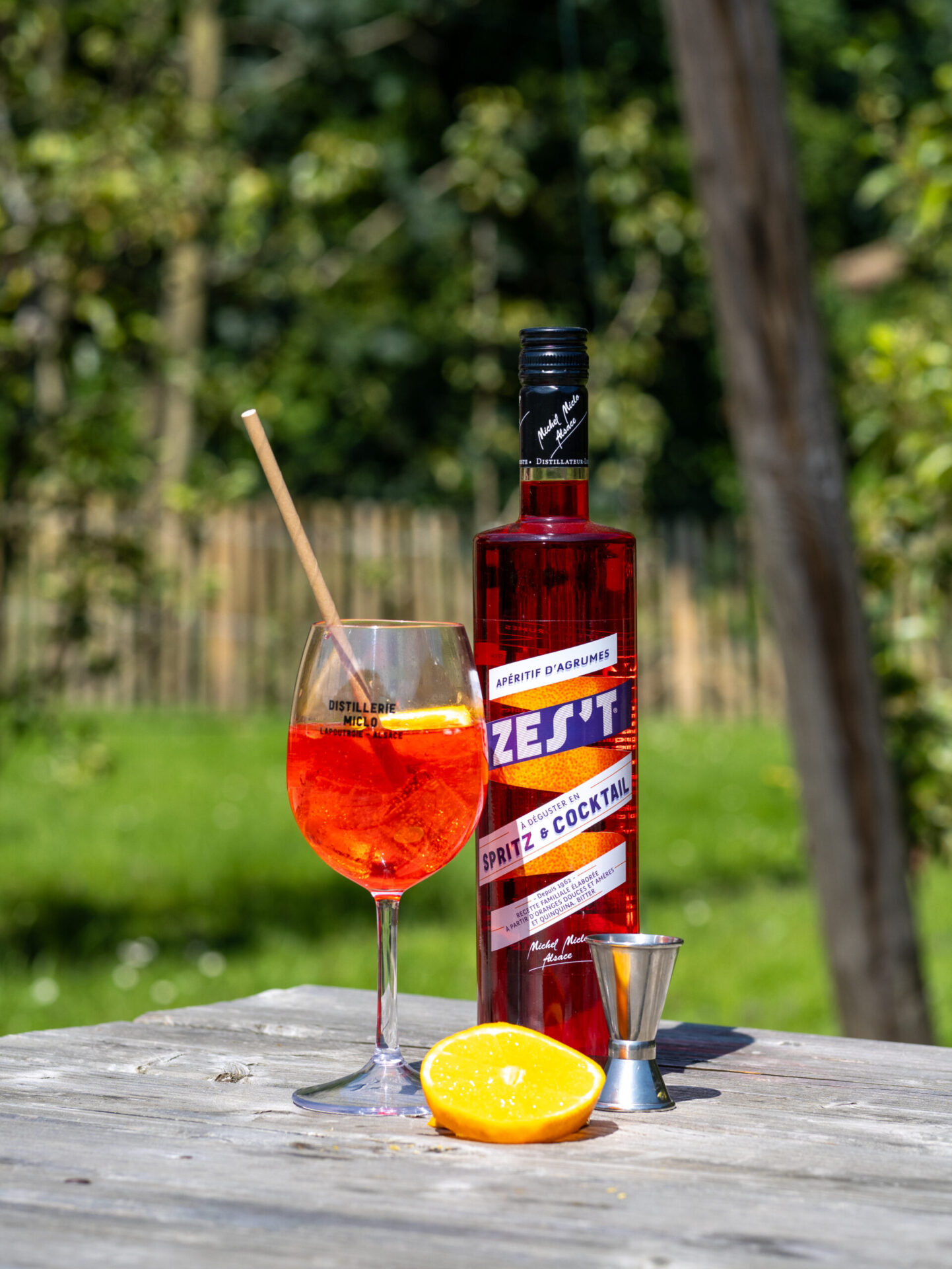 bouteille de spritz alsacien dans la nature avec un verre du cocktail