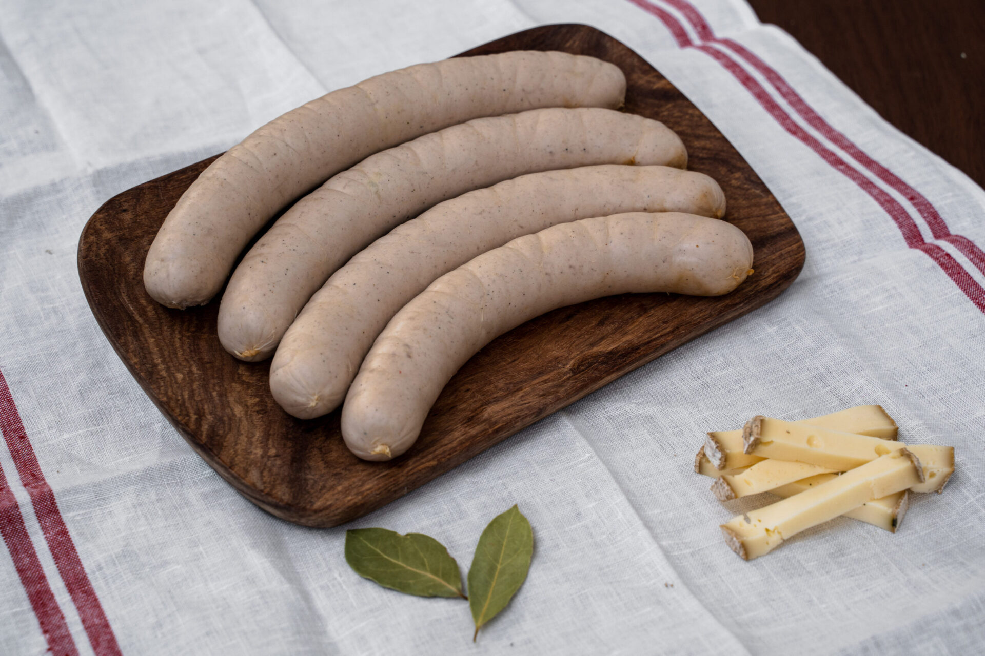 4 saucisses blanches sur planche en bois et torchon alsacien