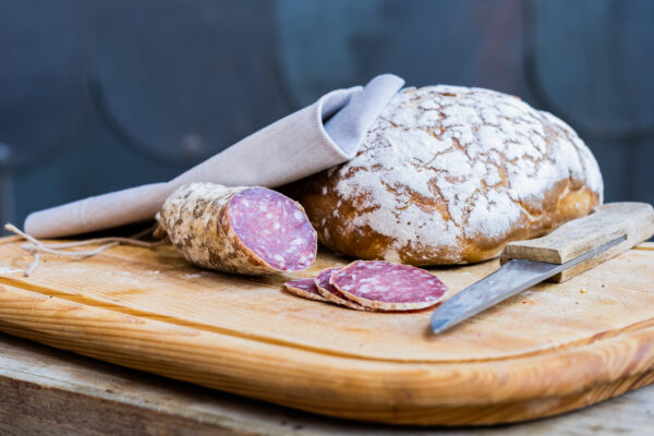 saucisson de cerf sur planche avec miche et couteau