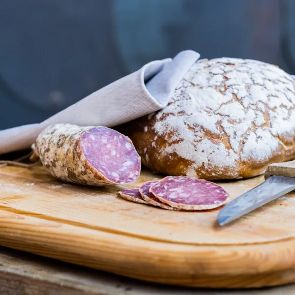 saucisson de cerf sur planche avec miche et couteau