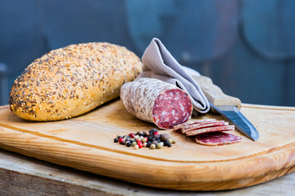 saucisson de sanglier au poivre sur planche avec couteau et graines de poivre