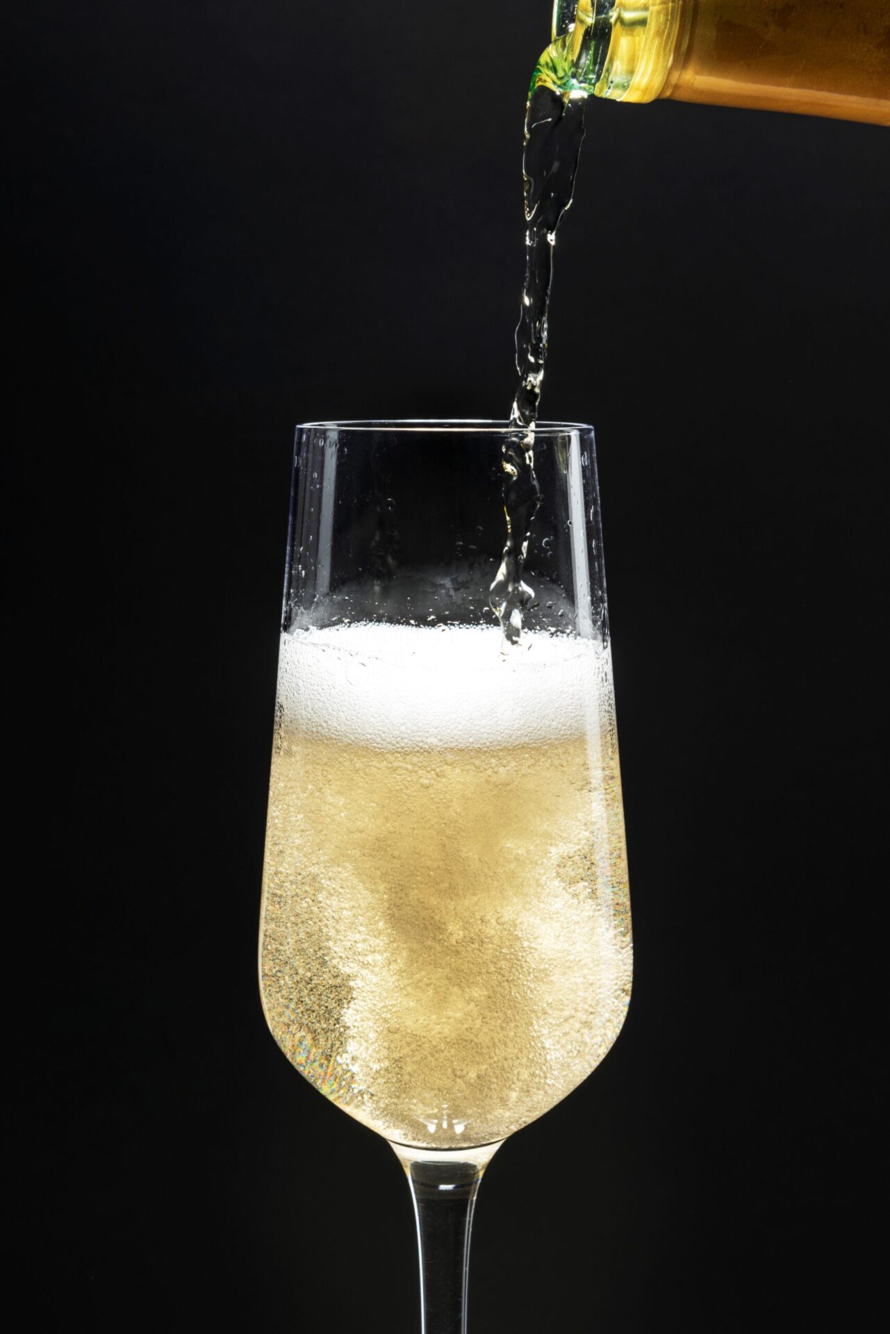 flûte à crémant en train d'être remplie sur fond noir